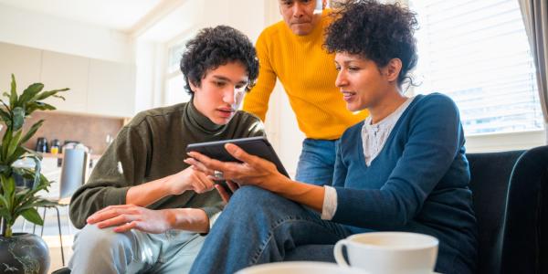 Family using digital tablet together in living room.