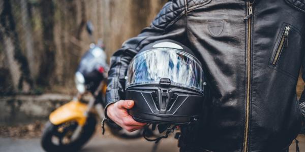 Motorcyclist holding helmet.